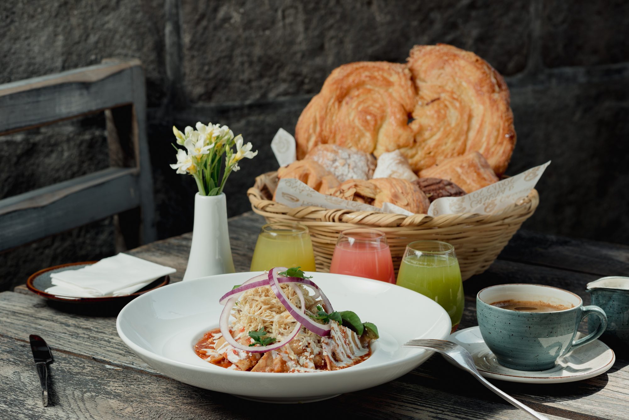 Desayuno en la Casona de los Sapos: chilaquiles, café, tres jugos y una canasta de pan de La Francesita con una palmera gigante.